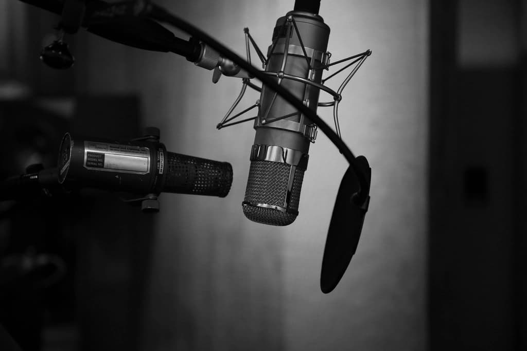 A condenser microphone on a boom arm in a recording studio